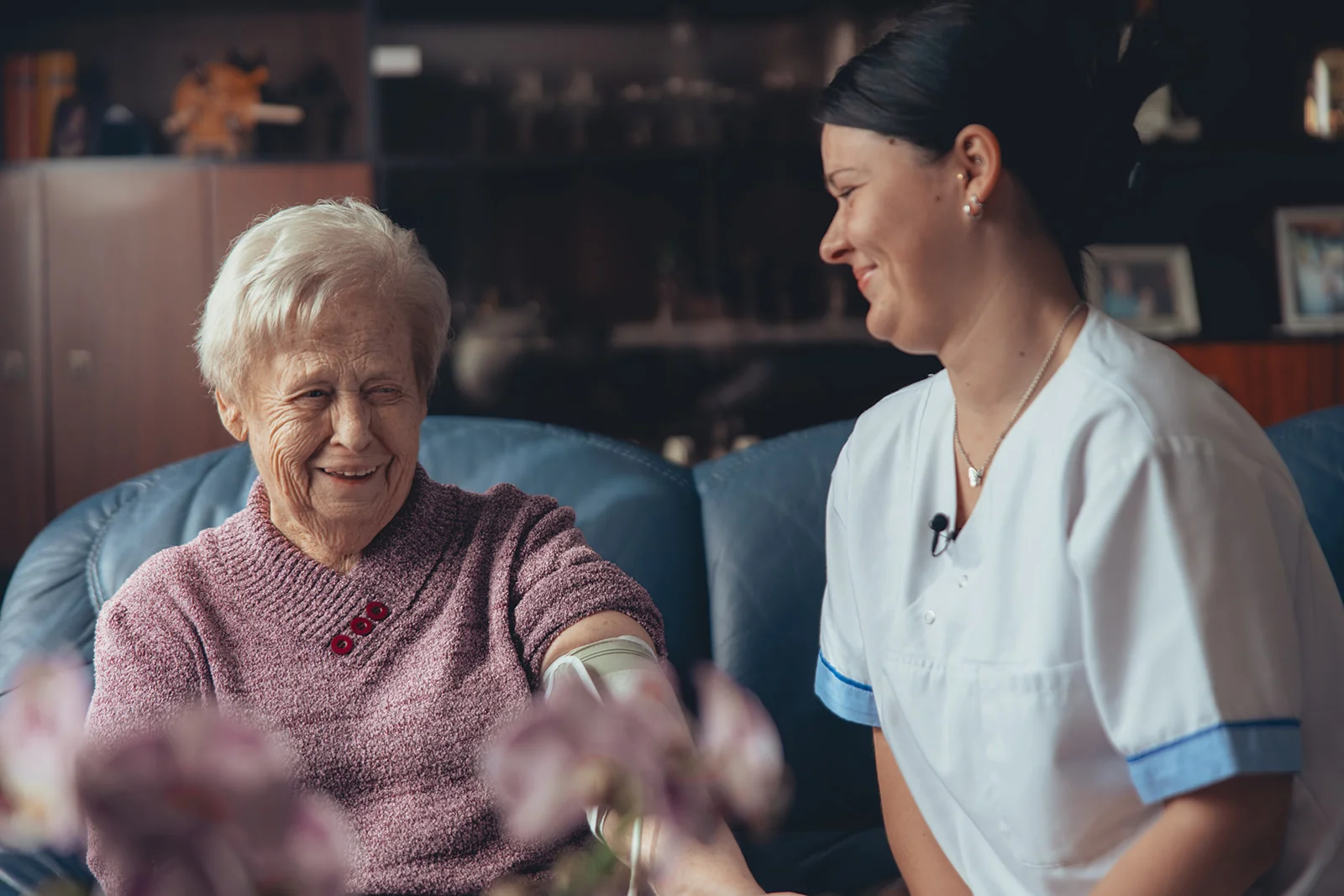 Eine Pflegekraft der Sozialstation Karlsruhe unterstützt eine Seniorin beim Anziehen von Kompressionsstrümpfen, ein Beispiel für die einfühlsame Betreuung und Unterstützung im Alltag. Die Szene veranschaulicht die Leistungen der Sozialstation in den Bereichen Fotografie, Studiofotografie, Projektbegleitung, Webdesign, Grafik und Videoproduktion sowie Animation.