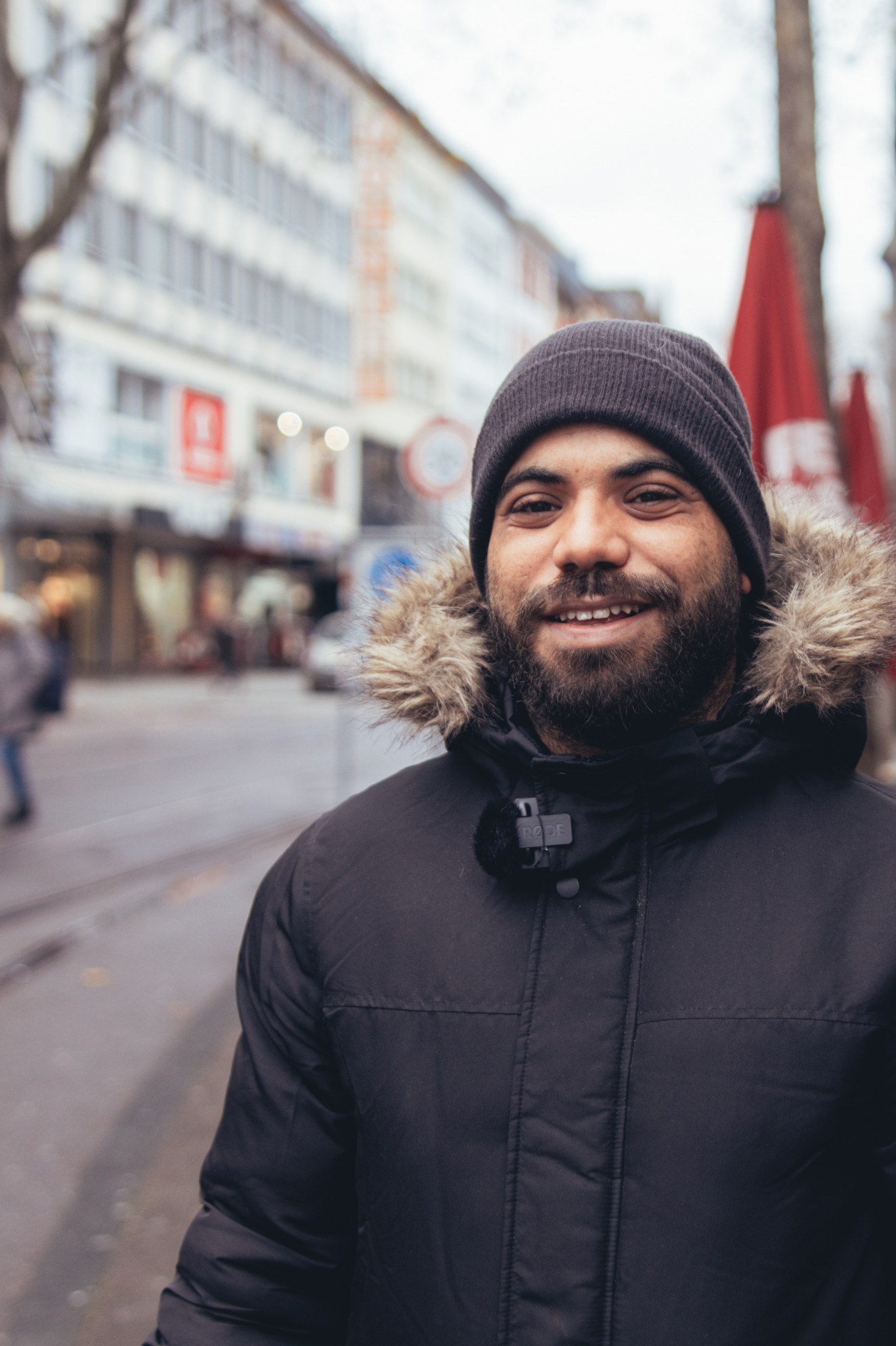 Ein Mann mit Mütze und Bart steht in der Kaiserstraße in Karlsruhe und wird für ein Video Content Projekt Interviewt