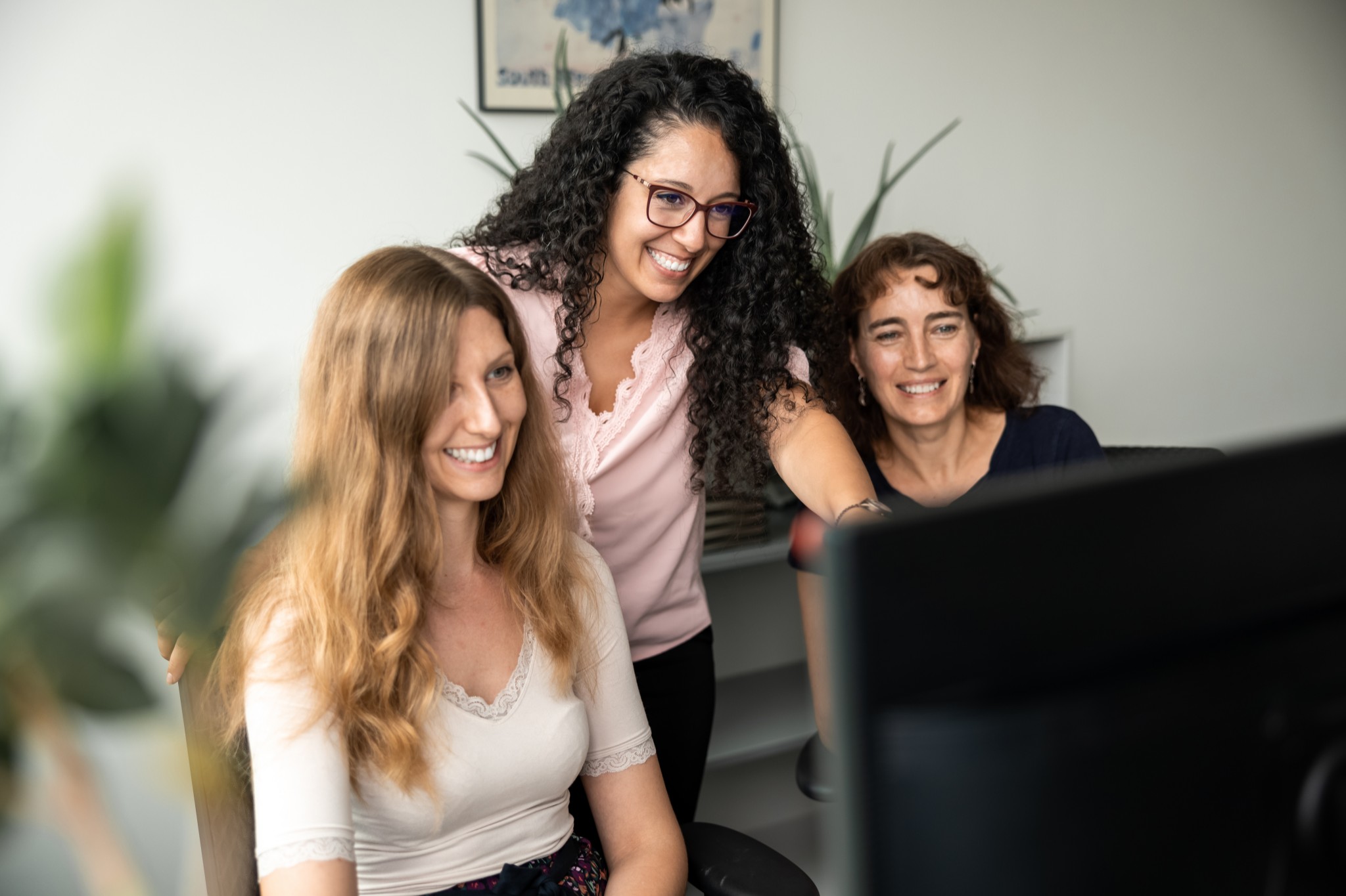 Drei Mitarbeiterinnen der Steuerkanzlei LPB schauen auf einen Bildschirm für ein Fotoshooting